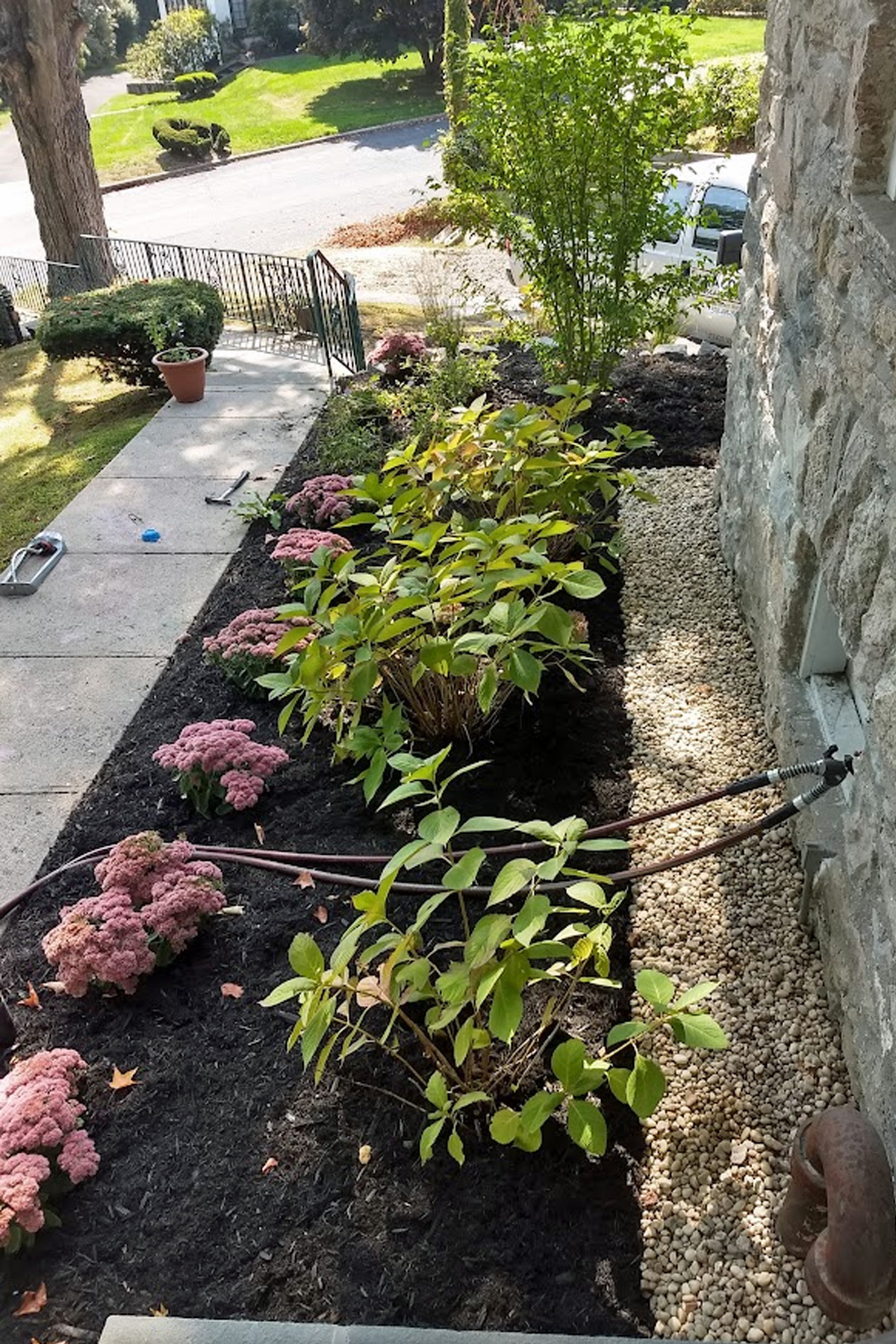 Thumbnail of completed plant bed, on the corner, with mulch and stone