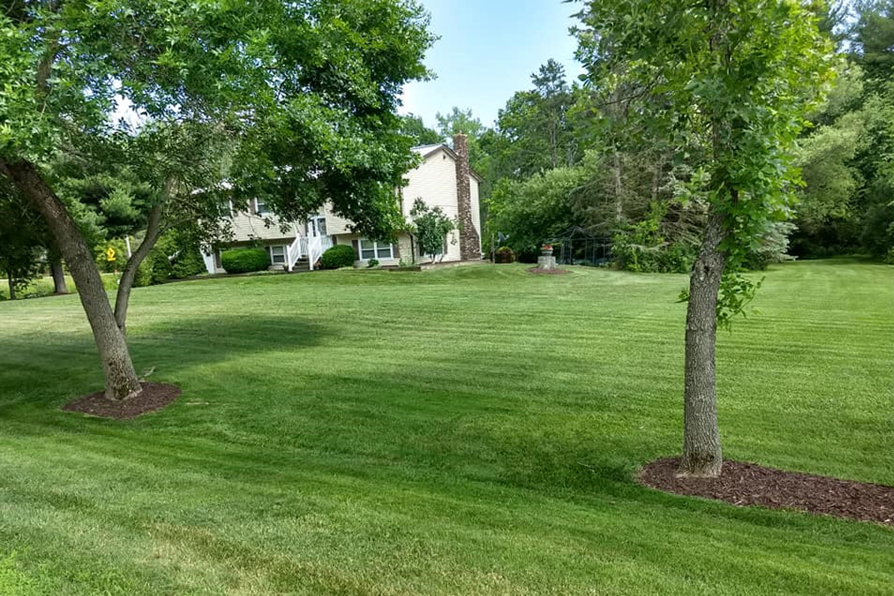 Thumbmnail image of a freshly mowed lawn with two weeded plantbeds and a house in the background