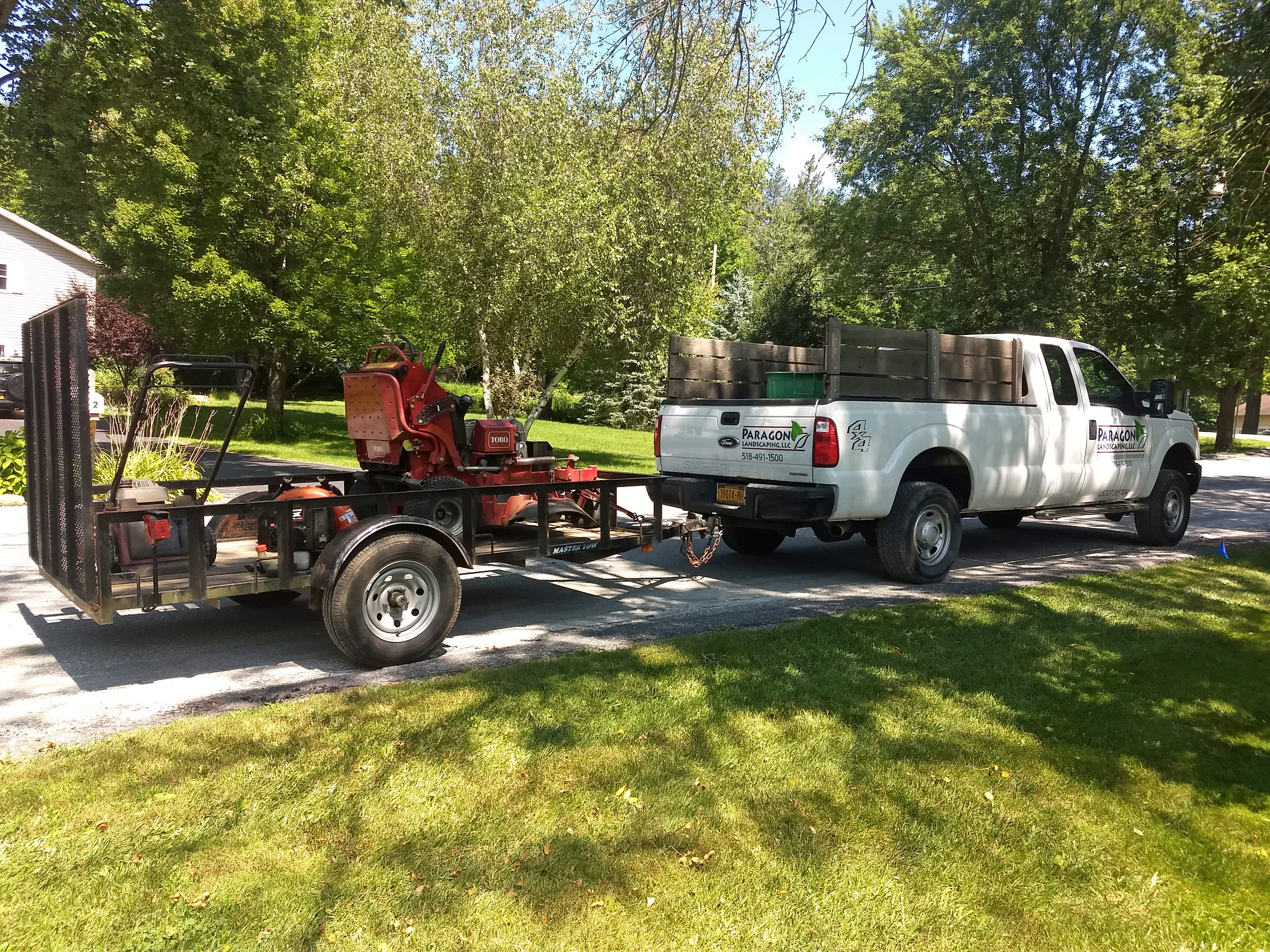 Thumbmnail image of a freshly mowed lawn with work truck and trailer holding a lawn mower